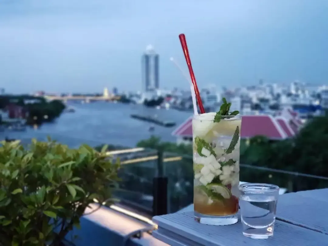 Rooftop drink overlooking the Chao Phraya River at dusk, Bangkok