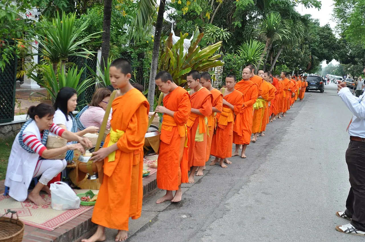Buddhist monks in Thailand receiving morning alms; offerings are placed in the bowl without touching the monk