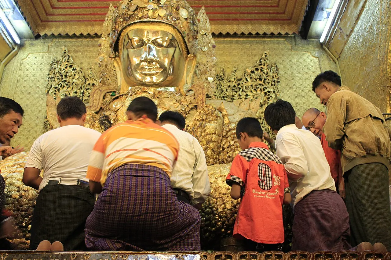 Devotees applying gold leaf to the Mahamuni Buddha