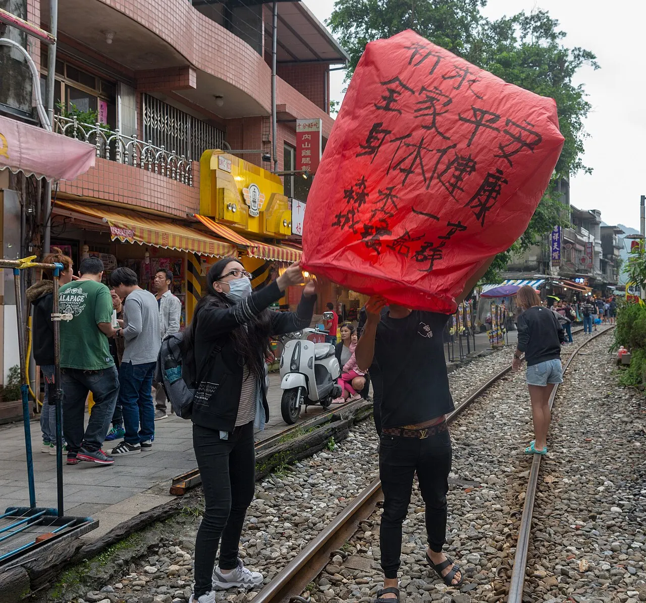 Visitors releasing a red sky lantern on the railway track at Shifen Old Street, Pingxi